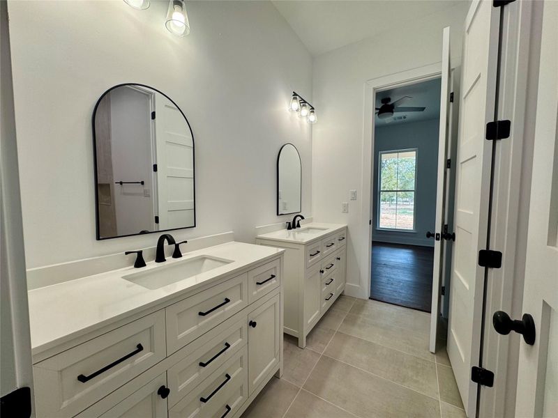 Bathroom featuring two vanities, light tile patterned floors, and ceiling fan Bathroom featuring two vanities, light tile patterned floors, and ceiling fan