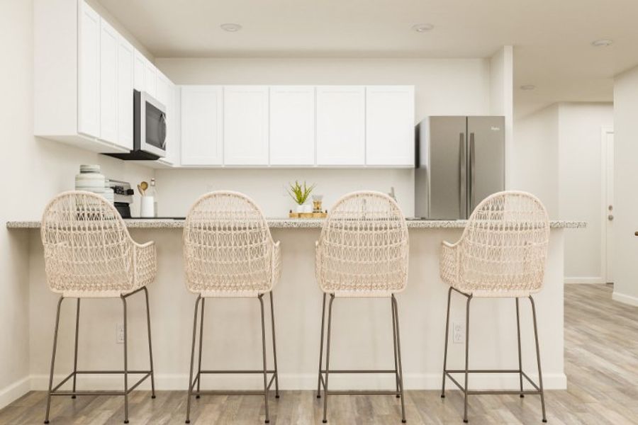 A kitchen with a bar stools.