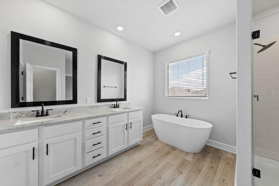 Master bathroom includes granite countertop, elongated mirror, and dual-vanity sinks. Relax in the large soaking tub or enjoy the spacious, standing shower.