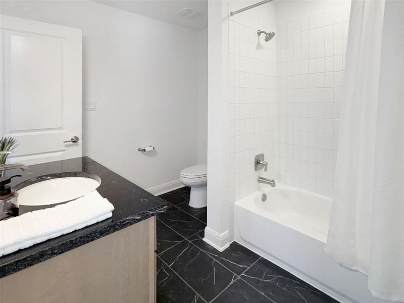Upstairs Full bath with shower / bath combo with shower curtain, vanity, and dark marble finish floors