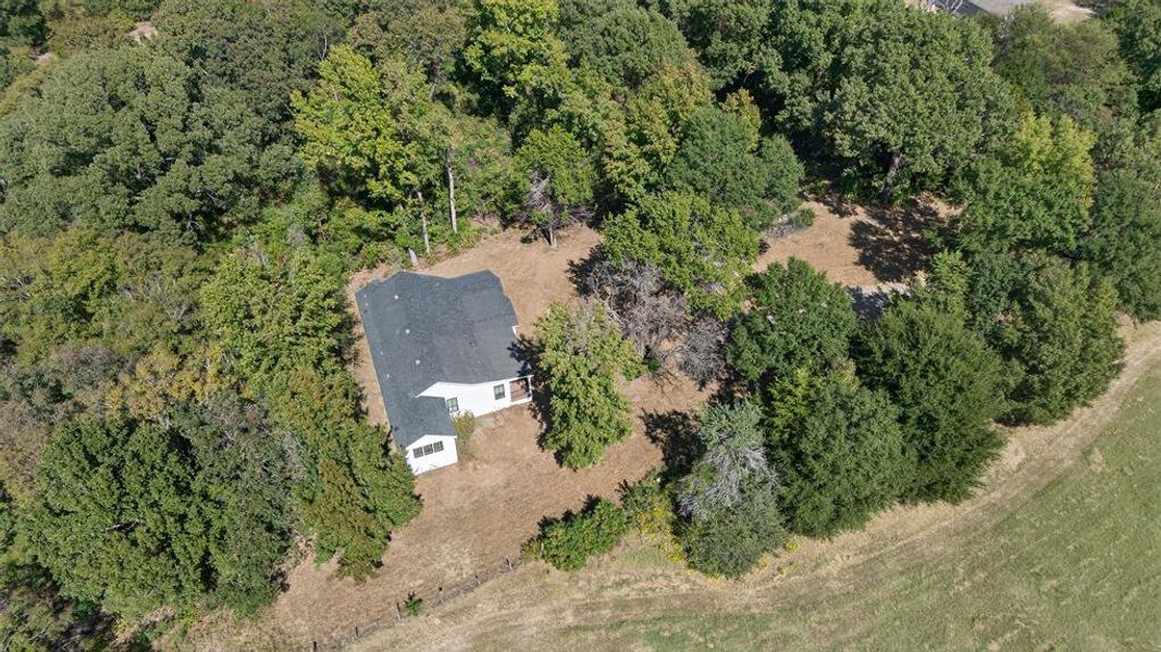 Aerial view of property and surrounding area featuring a forest