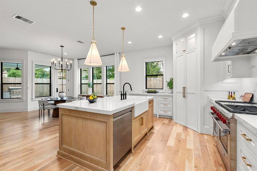 Designer selected pendant lighting grace the Large quartz island w/ Farm style sink.