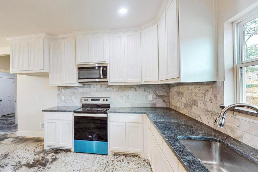 Kitchen featuring plenty of natural light, sink, white cabinetry, and stainless steel appliances