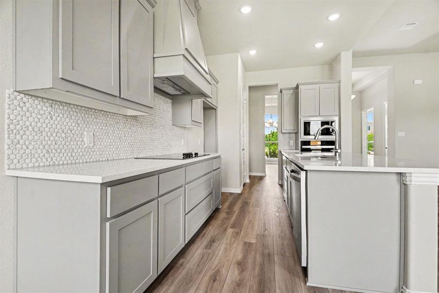 Modern kitchen featuring light gray cabinetry, light-toned countertops, and wood-finish flooring Modern kitchen featuring light gray cabinetry, light-toned countertops, and wood-finish flooring