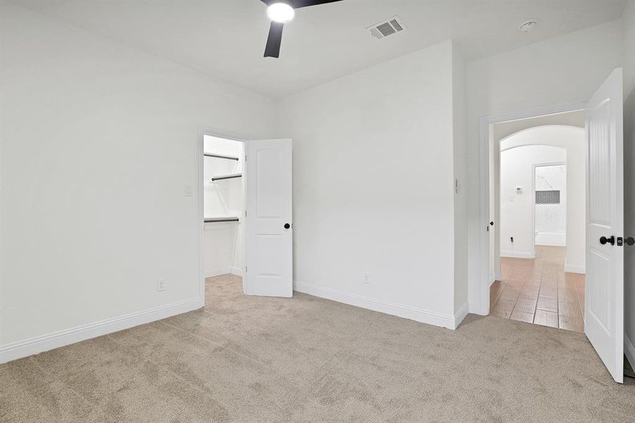 Unfurnished bedroom with light carpet, a closet, ceiling fan, and a spacious closet