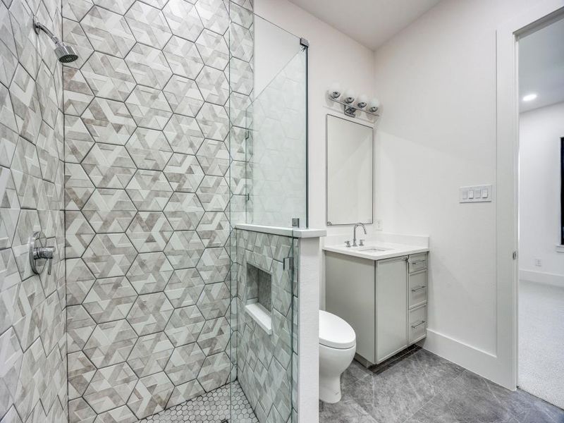 Bathroom featuring tile patterned floors, toilet, a tile shower, and vanity