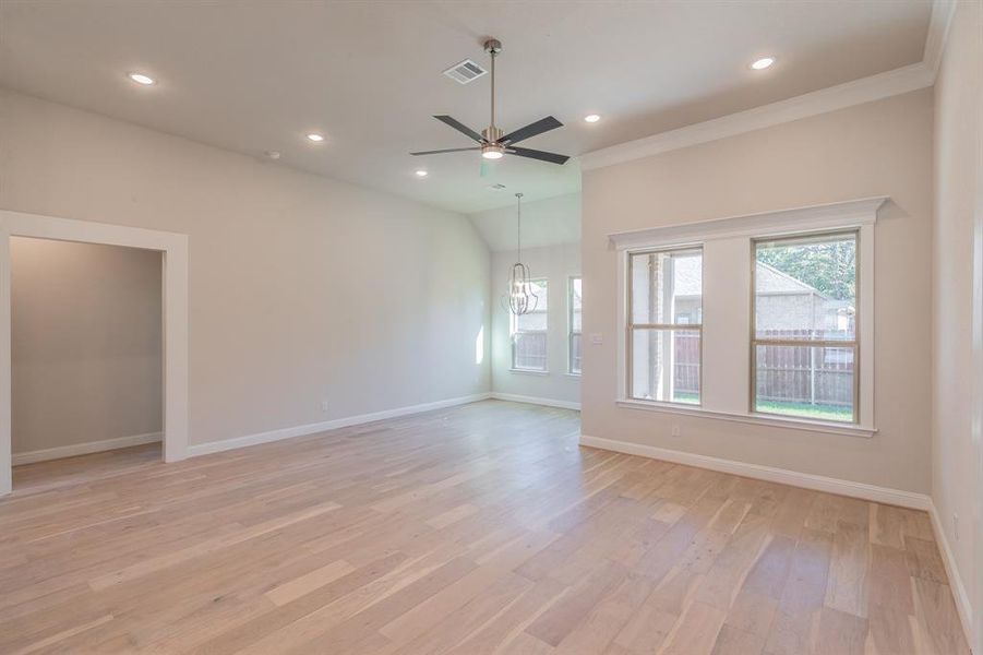 Unfurnished room with ceiling fan with notable chandelier, ornamental molding, and light hardwood / wood-style flooring