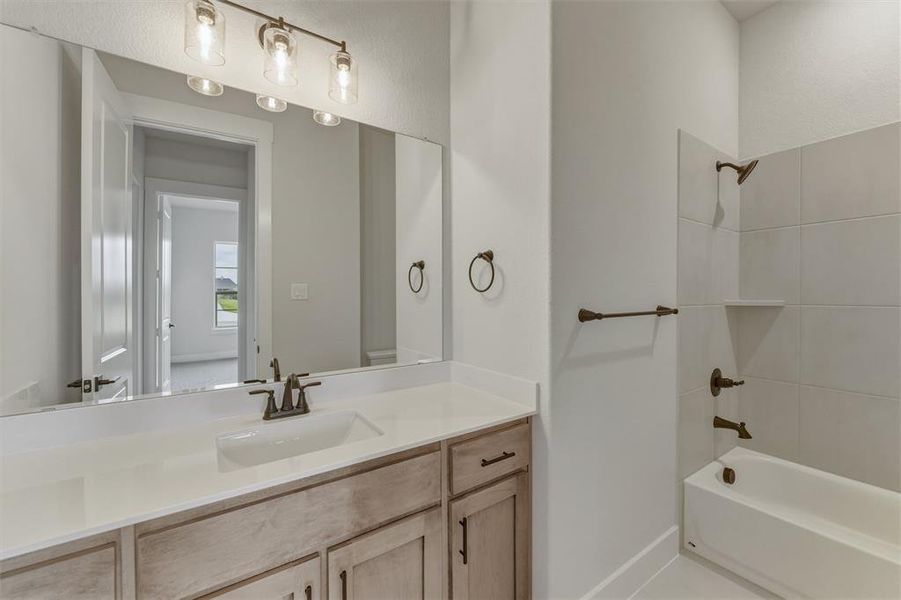 Bathroom featuring a light wood-finish vanity with a single basin, white countertop, and oil-rubbed bronze fixtures Bathroom featuring a light wood-finish vanity with a single basin, white countertop, and oil-rubbed bronze fixtures