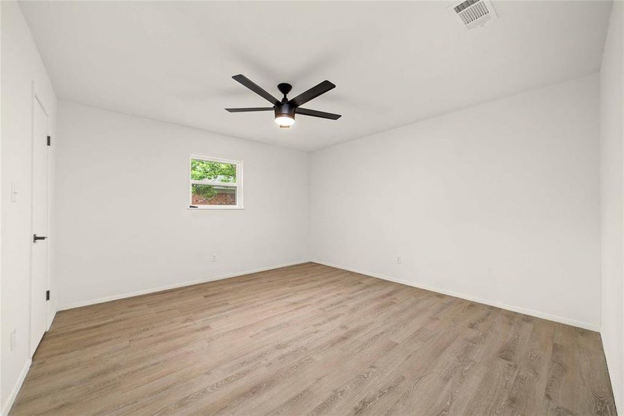 Empty room with baseboards, ceiling fan, visible vents, and light wood-style floors Empty room with baseboards, ceiling fan, visible vents, and light wood-style floors
