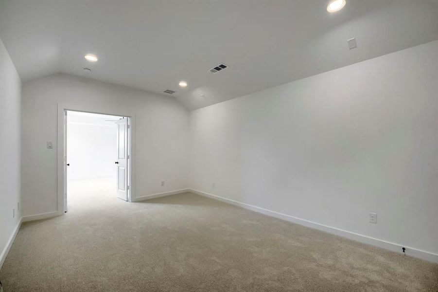 Spacious room featuring vaulted ceilings, recessed lighting, neutral carpet flooring, and double doors Spacious room featuring vaulted ceilings, recessed lighting, neutral carpet flooring, and double doors