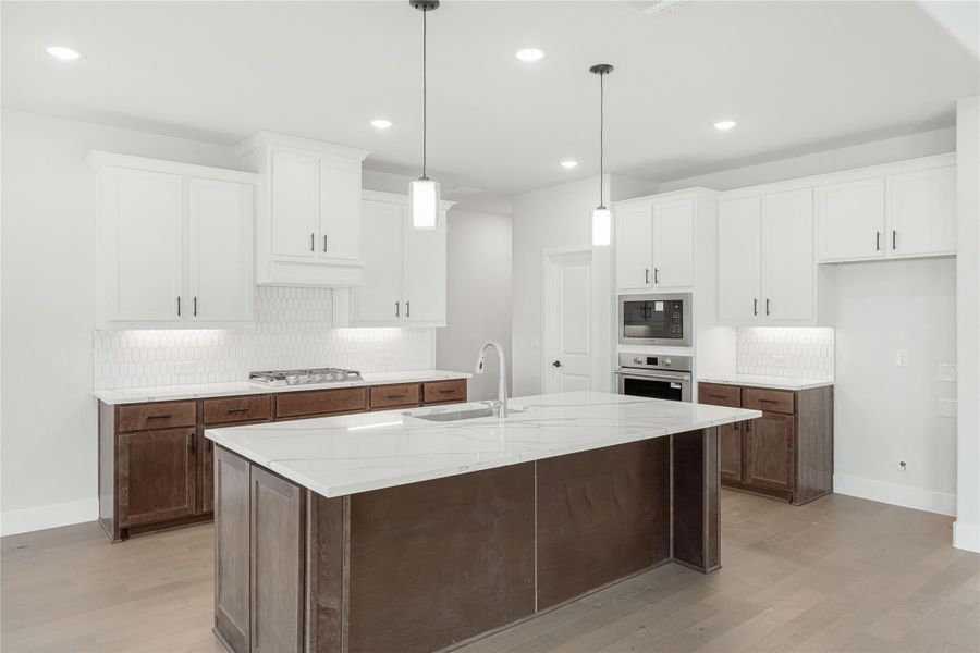 Kitchen with large island, white upper cabinets, dark lower cabinets, quartz countertops, and stainless steel appliances Kitchen with large island, white upper cabinets, dark lower cabinets, quartz countertops, and stainless steel appliances