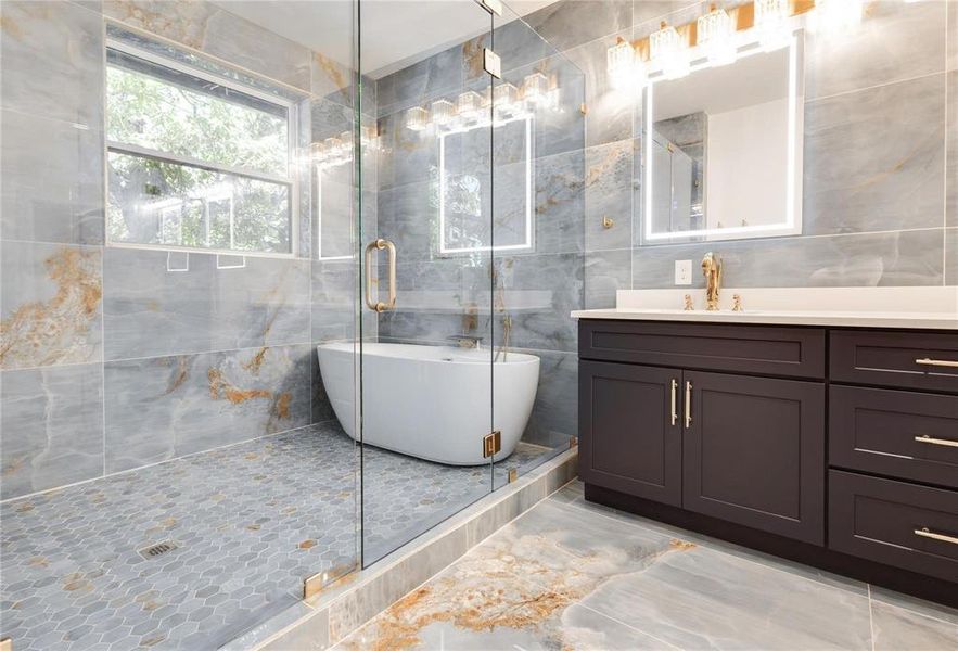 Bathroom featuring independent shower and bath, vanity, and tile walls