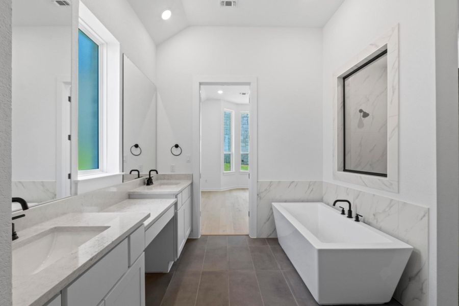 Full bath featuring a freestanding bath, vanity, tile walls, tile patterned floors, and wainscoting