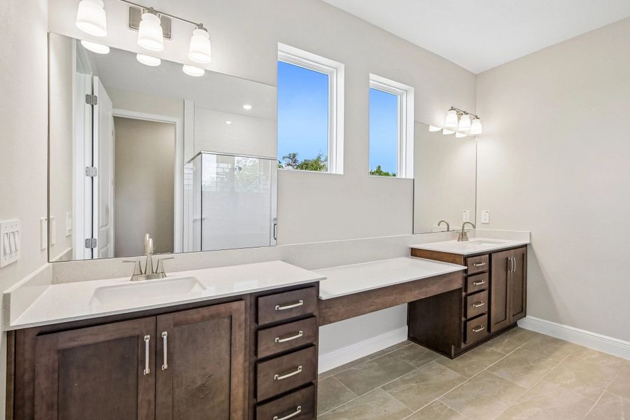 The primary bathroom features aspects of AW Collection® Roosevelt and has separate sinks and two upper windows for extra natural light