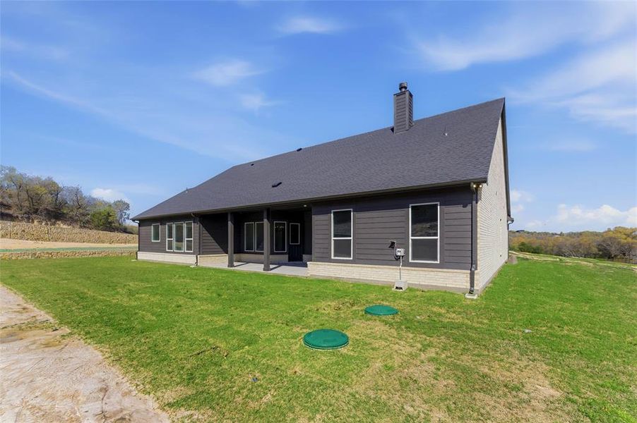 Rear view of property with a patio area, a yard, and a chimney