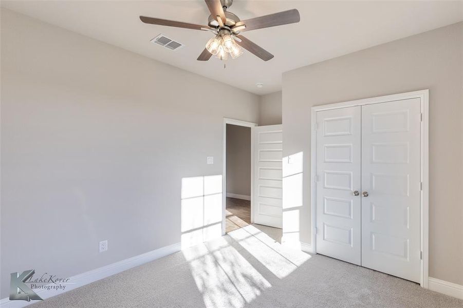Unfurnished bedroom featuring carpet, a ceiling fan, and a closet