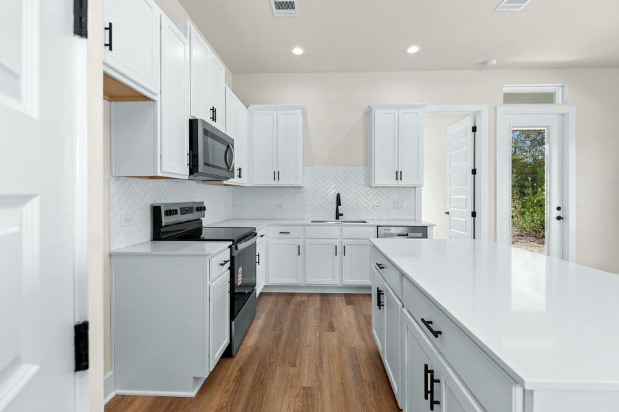 Kitchen with white cabinetry, stainless steel appliances, tasteful backsplash, light wood finished floors, and recessed lighting
