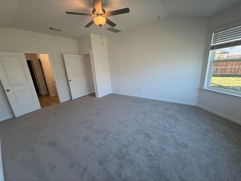 Unfurnished bedroom with lofted ceiling, carpet flooring, and a ceiling fan