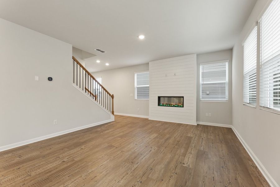 A room with a wood floor and a wood floor with a staircase. A room with a wood floor and a wood floor with a staircase.