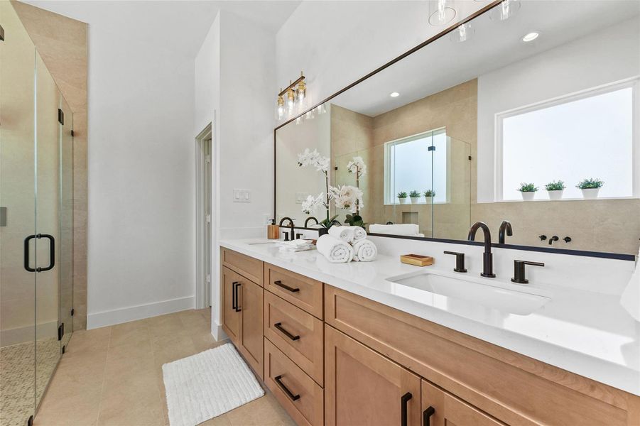 Luxurious primary bathroom with dual sinks, quartz countertops, sleek black fixtures, a frameless glass shower, and abundant natural light. Luxurious primary bathroom with dual sinks, quartz countertops, sleek black fixtures, a frameless glass shower, and abundant natural light.