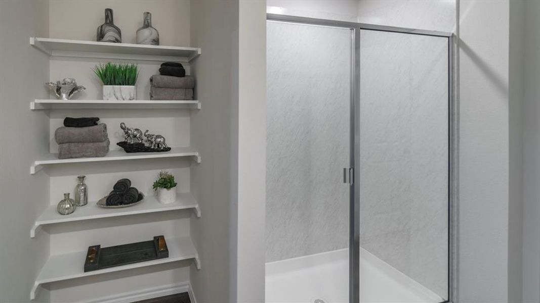 Built-in shelving unit with multiple white shelves complemented by a shower enclosure featuring a white base and sliding frosted glass doors with metal framing Built-in shelving unit with multiple white shelves complemented by a shower enclosure featuring a white base and sliding frosted glass doors with metal framing