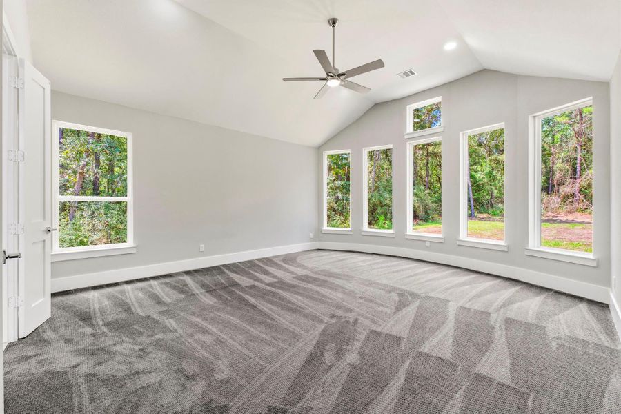 A wall of windows surrounds the primary retreat with tranquil wooded views and abundant natural light.