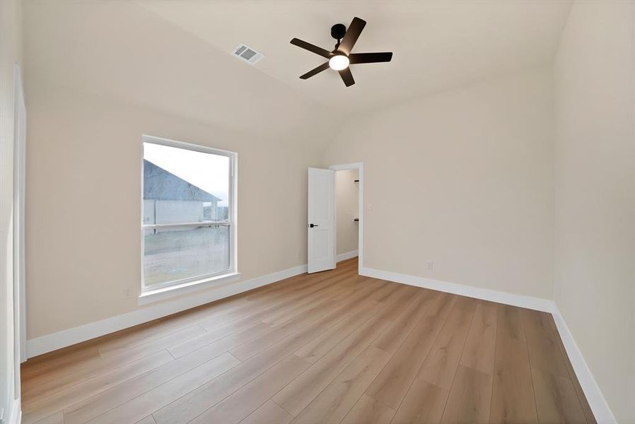 Spare room with light wood-style flooring, vaulted ceiling, and a ceiling fan Spare room with light wood-style flooring, vaulted ceiling, and a ceiling fan