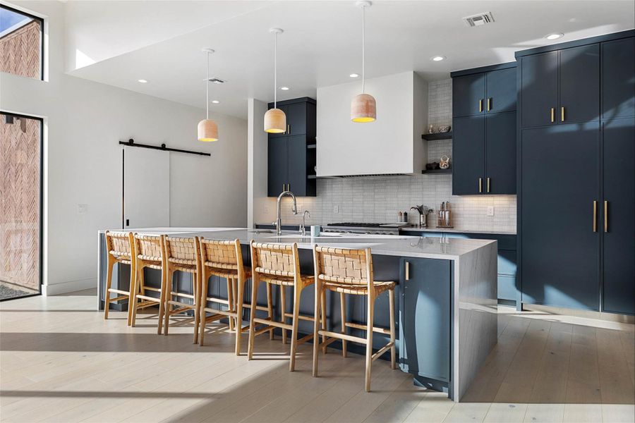 Kitchen with a kitchen breakfast bar, open shelves, tasteful backsplash, decorative light fixtures, and light stone countertops
