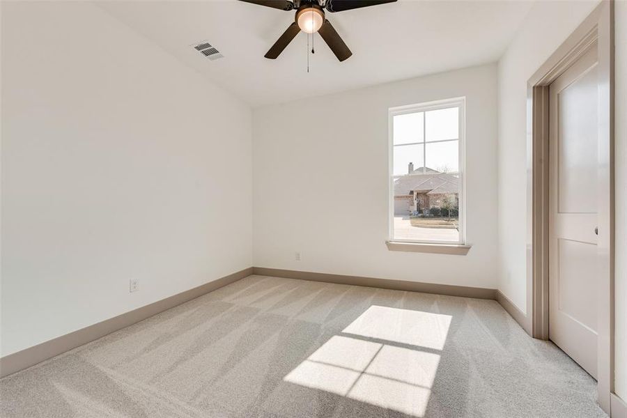 Carpeted spare room featuring ceiling fan