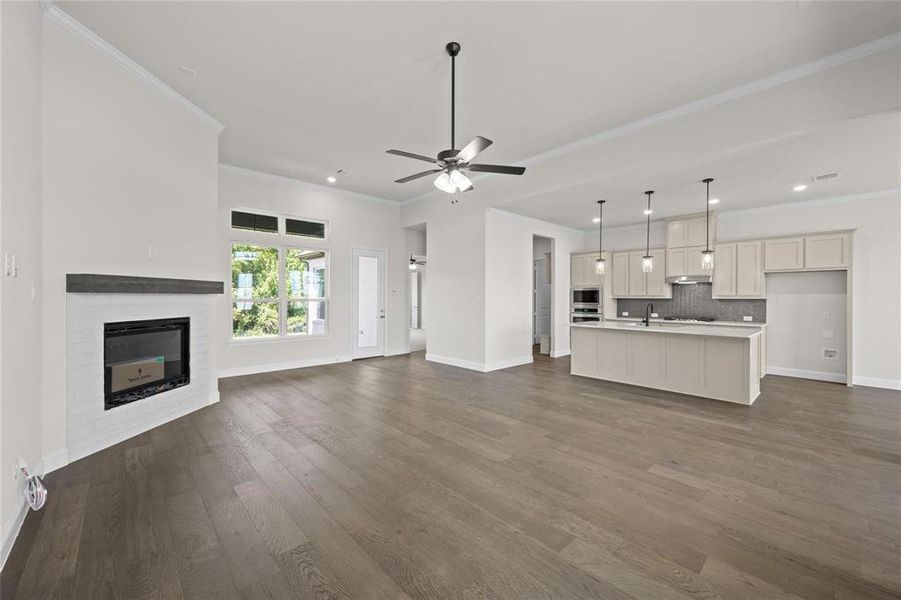 Unfurnished living room with ceiling fan, ornamental molding, sink, and dark hardwood / wood-style flooring