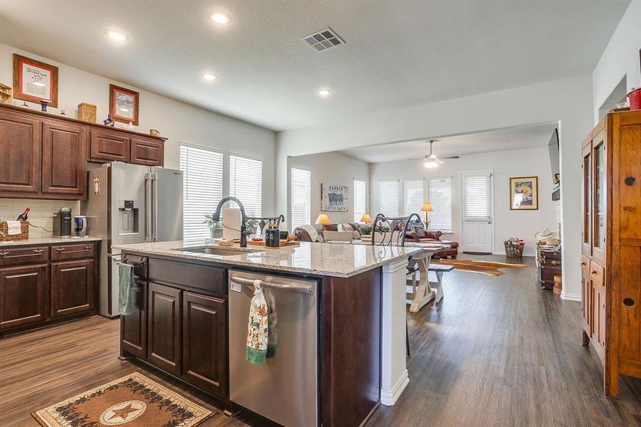 Kitchen with appliances with stainless steel finishes, plenty of natural light, dark brown cabinets, light stone counters, and recessed lighting Kitchen with appliances with stainless steel finishes, plenty of natural light, dark brown cabinets, light stone counters, and recessed lighting