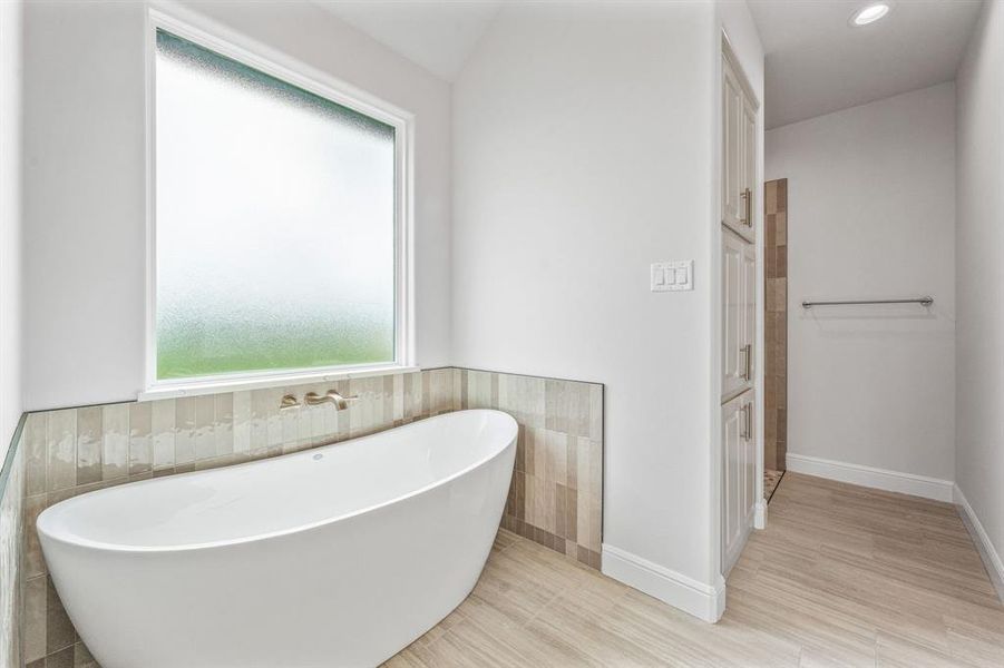 Full bath featuring tile walls, a freestanding bath, baseboards, recessed lighting, and wainscoting