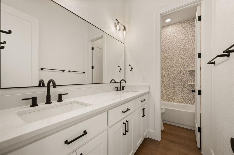 Bathroom featuring wood finished floors, double vanity, and tub / shower combination Bathroom featuring wood finished floors, double vanity, and tub / shower combination