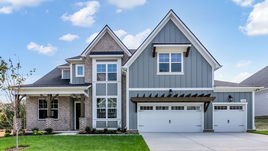 Elegant gray house with gabled roof and brick facade. Enjoy serene Brush Creek surroundings.