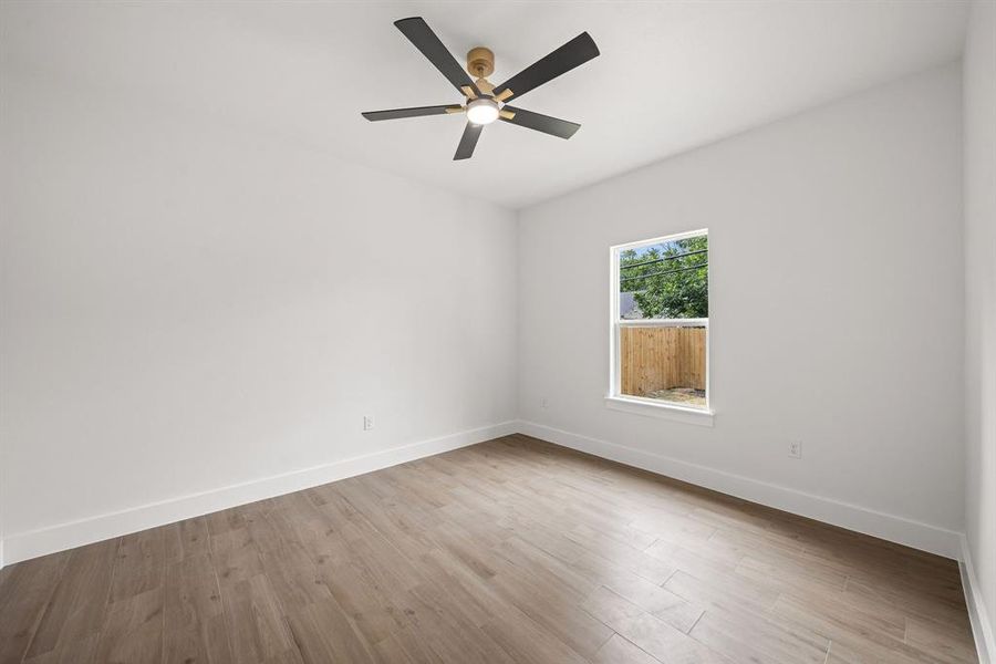 Bright room featuring wood-finish flooring, a contemporary ceiling fan, and crisp white walls