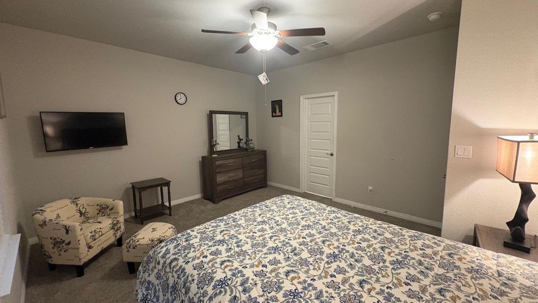 Relax in comfort with a ceiling fan overhead and soft carpet underfoot in this cozy sleeping area.