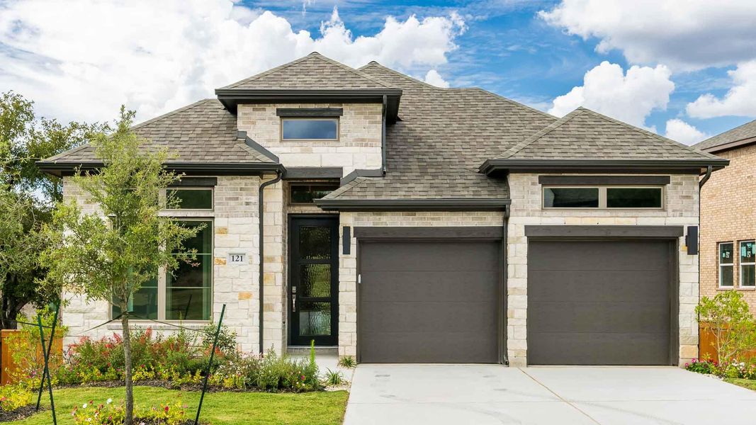 French provincial home featuring stone siding, a shingled roof, concrete driveway, a garage, and a front lawn French provincial home featuring stone siding, a shingled roof, concrete driveway, a garage, and a front lawn
