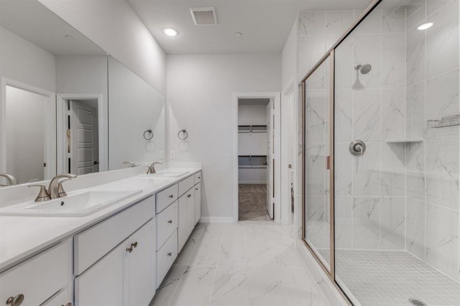 Bathroom with a sink, a marble finish shower, marble finish floor, and visible vents