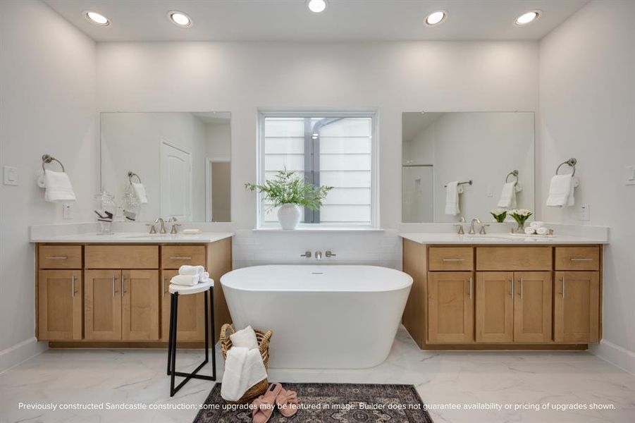 Step into an oasis featuring a vessel tub set between dual vanities, framed by custom wood cabinets and quartz countertops, for an unwavering indulgence.