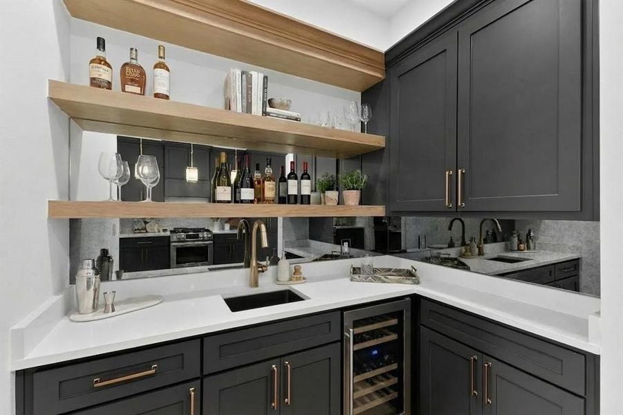 Indoor wet bar with open shelves, gray cabinetry, beverage cooler, light stone countertops, and stainless steel range with gas stovetop