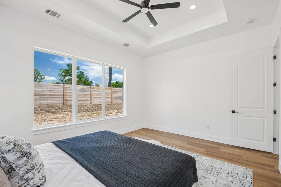 Clean lines and a tray ceiling define this minimalist bedroom space with hardwood flooring. Clean lines and a tray ceiling define this minimalist bedroom space with hardwood flooring.