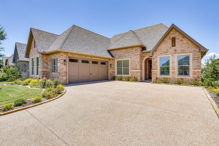 Brick and stone facade residence featuring a multi-car driveway, arched entryway, and front landscaping