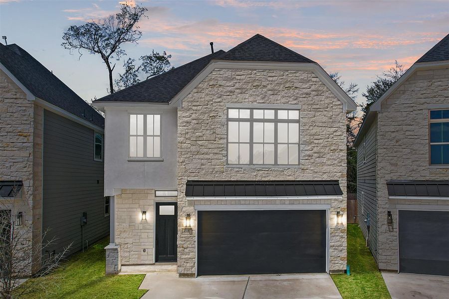 This modern, two-story home with stone façade and large windows features a two-car garage. The contemporary design provides a stylish and functional space.