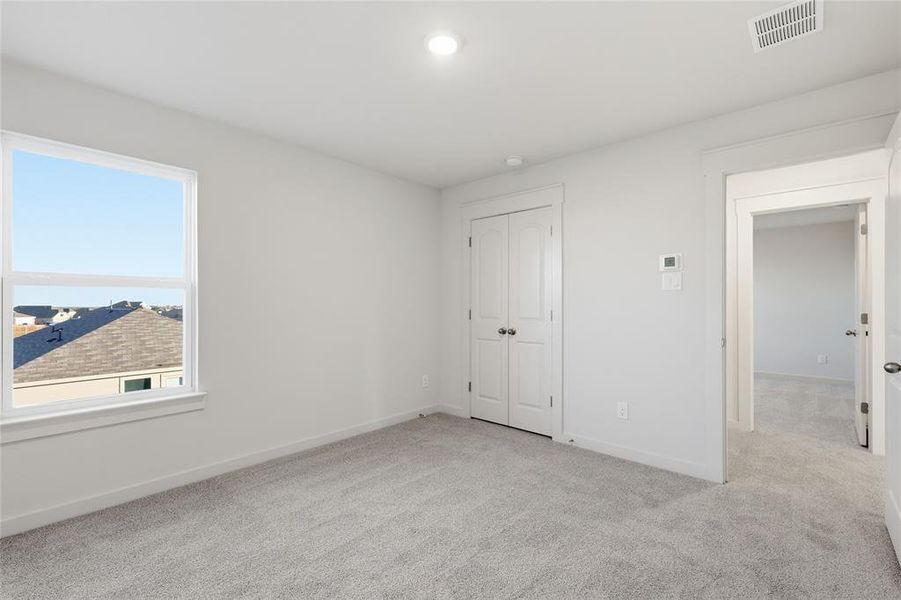 Carpeted room featuring a white-framed window, double-door closet, recessed lighting, and a white baseboard trim Carpeted room featuring a white-framed window, double-door closet, recessed lighting, and a white baseboard trim