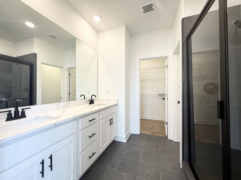 Bathroom featuring a stall shower, double vanity, recessed lighting, and a walk in closet
