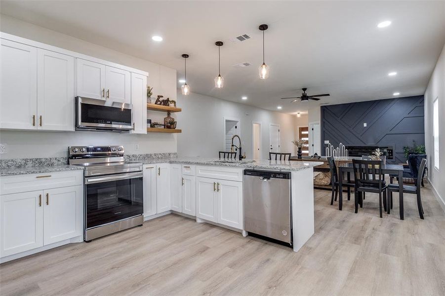 Kitchen with ceiling fan, light hardwood / wood-style floors, appliances with stainless steel finishes, and kitchen peninsula