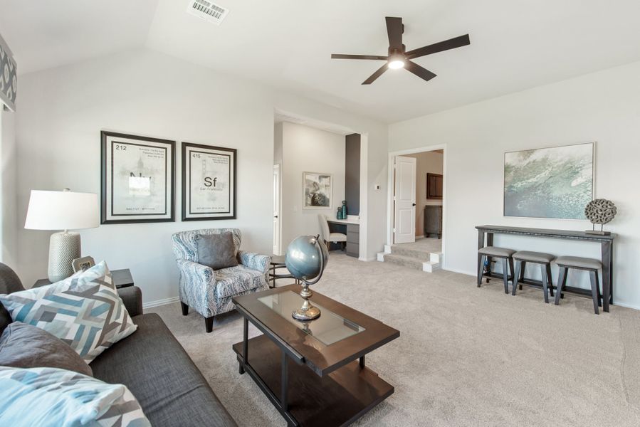 Carpeted living room with ceiling fan, sofa, accent chairs, and dark wood coffee table