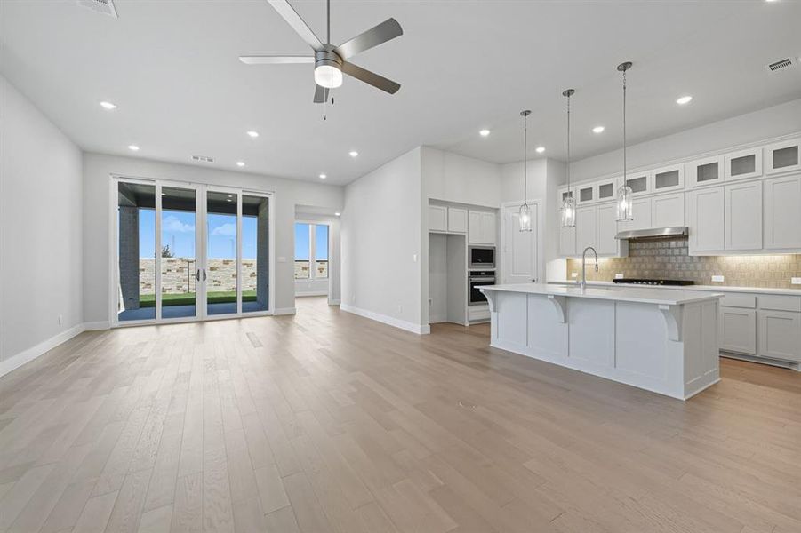 Kitchen featuring white cabinets, a breakfast bar, open floor plan, a center island with sink, and tasteful backsplash Kitchen featuring white cabinets, a breakfast bar, open floor plan, a center island with sink, and tasteful backsplash