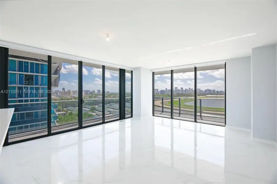 Floor-to-ceiling glass walls, polished white tile flooring, expansive corner layout, and structural balcony railing