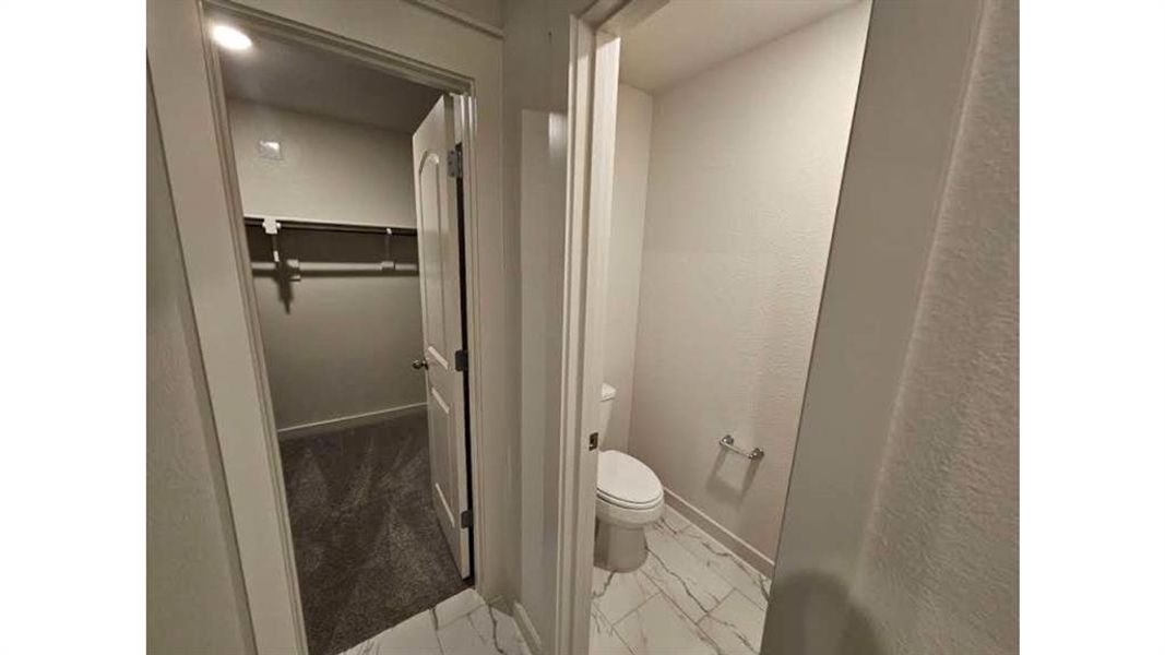 Powder room with marble-look tile flooring and white toilet Powder room with marble-look tile flooring and white toilet
